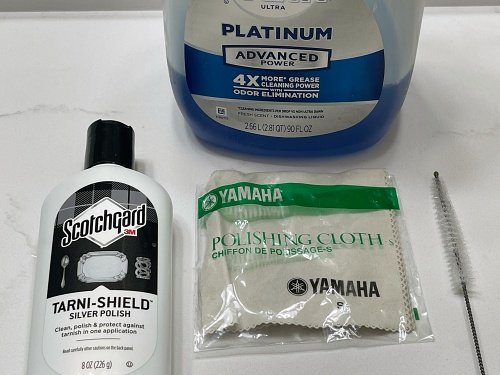 My personal cleaning supplies, a bottle of Dawn dish soap, a Yamaha polishing cloth, a bottle of Scotchgard Tarni-shield silver polish, and a trumpet mouthpiece brush.
